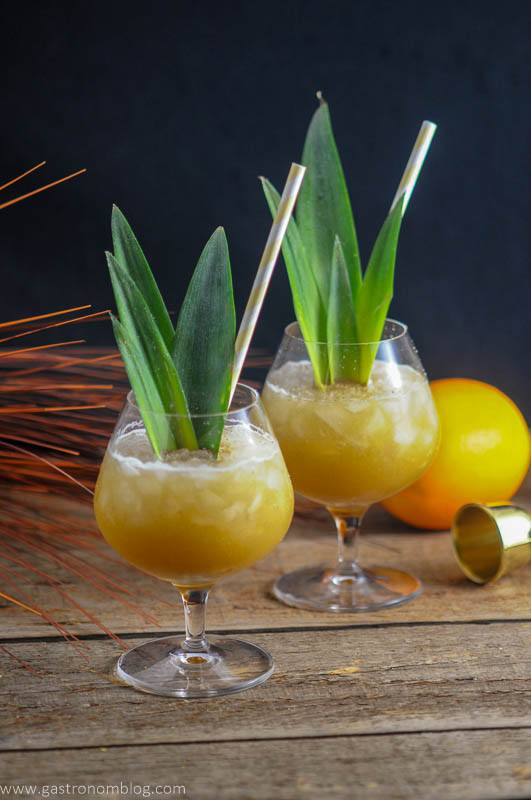 Coconut Rum Painkillers, yellow cocktails in glasses with crushed ice, pineapple fronds and yellow straws