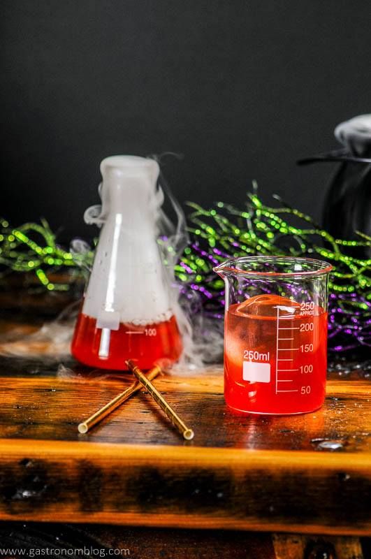 Red Halloween Cocktail in laboratory beakers. Gold straws and silver cocktail shaker. 
