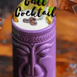 Purple tiki mug with foam, coffee beans and pineapple fronds