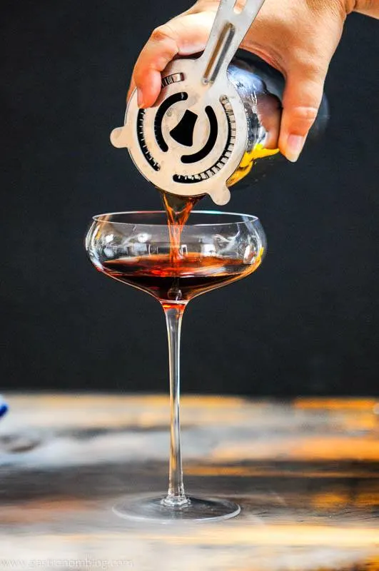 Red Cynar Negroni being poured into coupe