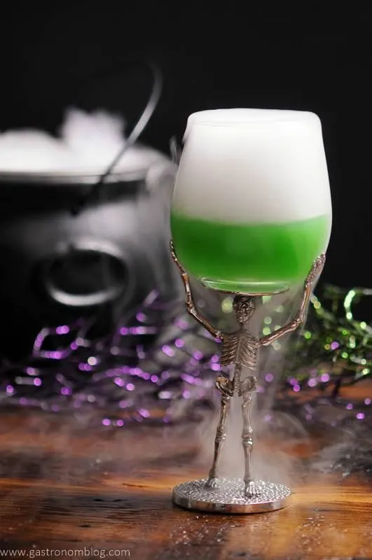 Green Fantastic Beasts cocktail in skeleton glass with dry ice, cauldron in background