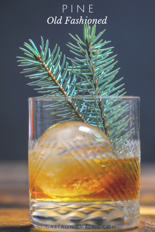 Pine flavored Old Fashioned in a rocks glass with an ice ball and pine branches