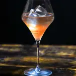 Cocktail in a tall wine glass with clear ice cubes