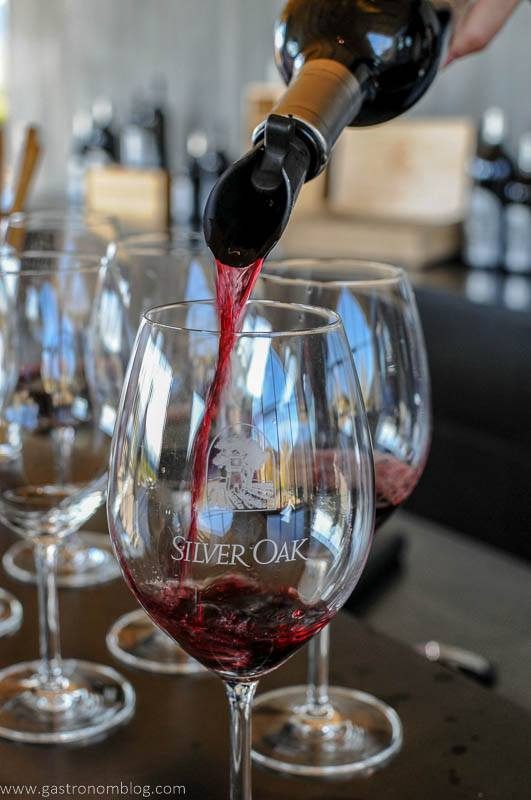 A wine glass from Silver Oak Winery is filled with red wine.