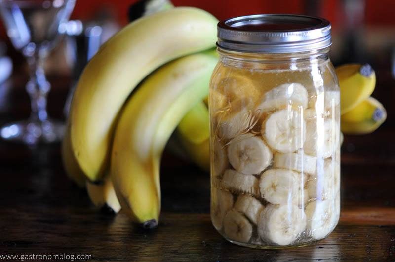 A mason jar filled with rum and banana slices to make homemade banana liqueur.