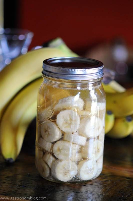 A mason jar filled with rum and banana slices to make homemade banana liqueur.