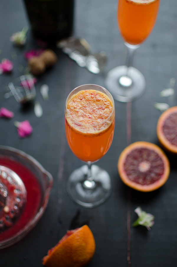 Top shot of orange cocktail in champagne coupe, blood orange slices, champagne bottle
