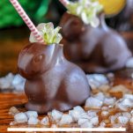 Hollow chocolate bunnies filled with crushed ice and a cocktail. Pink and white striped straw and flowers.
