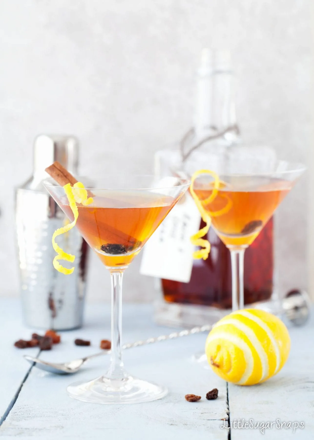 Gold cocktails in martini glasses, liqueur in bottle, lemon and spices