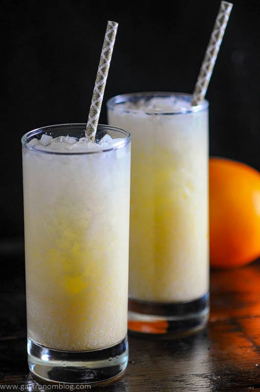 Orange Dreamsicle, orange cocktails in tall glasses with ice and purple straws, orange in background