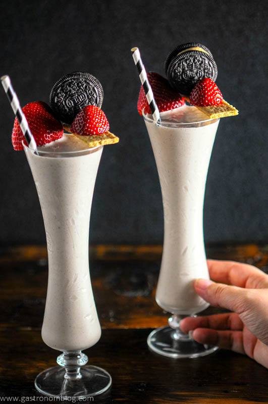 Pink milkshakes in tall glasses, strawberries and oreos on graham crackers, black and white straws