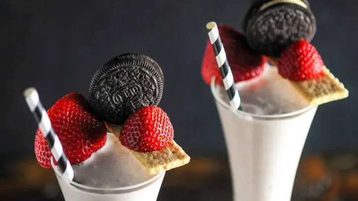 strawberry shakes, graham crackers, strawberries and oreos on top with black and white straws