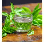 Simple syrup made with basil in jar with basil leaves behind
