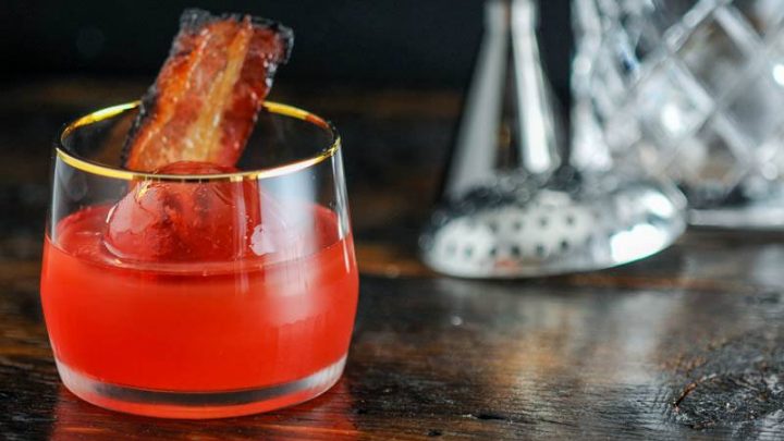 Negroni in gold rimmed cocktail glass, bacon garnish