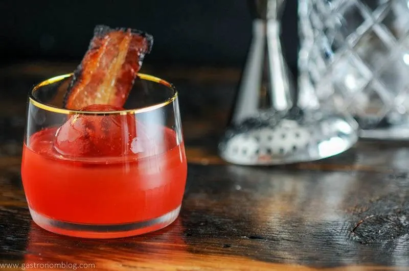 Cocktail in gold rimmed rocks glass with bacon