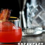 Red cocktail with bacon, bottle in background
