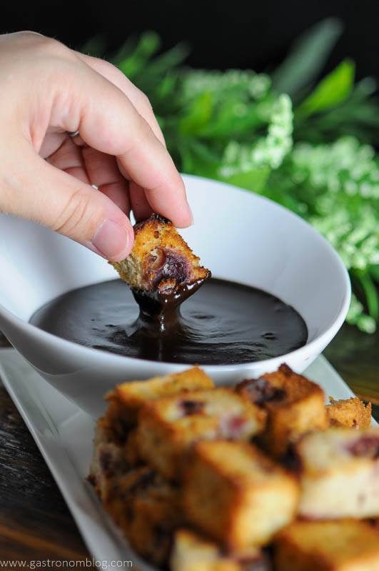 Dipping cake into fudge sauce in a white bowl