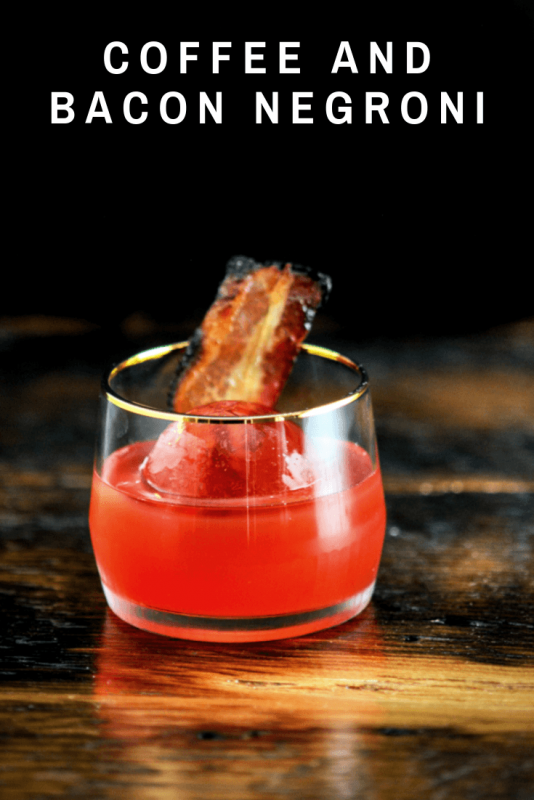 Cocktail in gold rimmed rocks glass with bacon slice
