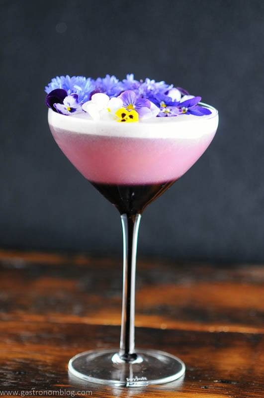 Purple coupe with egg white cocktail, edible flowers