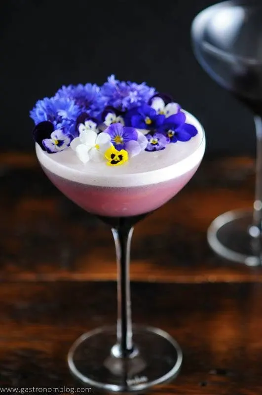 Edible flowers on egg foam in purple coupe