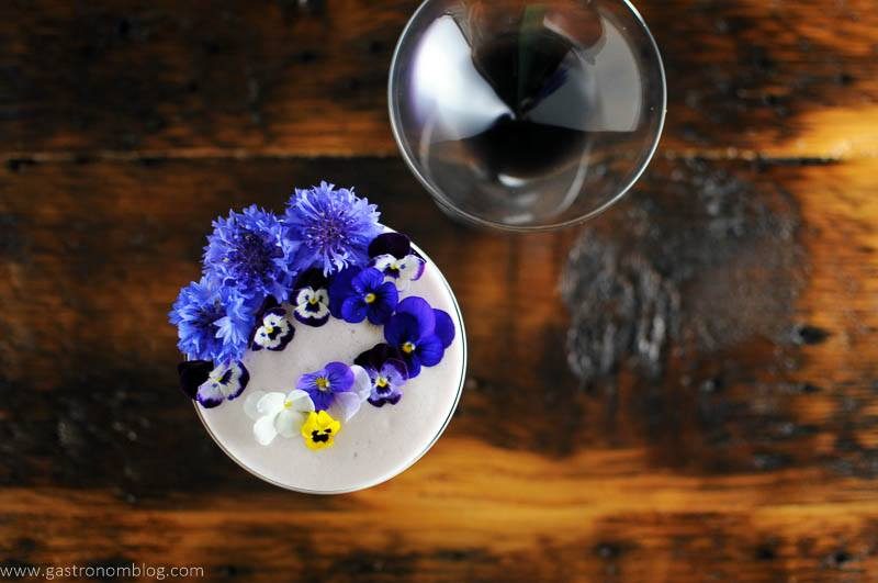 Edible flowers on top of cocktail and empty coupe, top shot