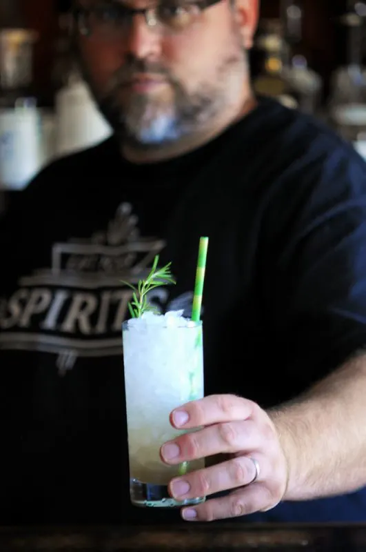 Man holding drink in a highball with straw