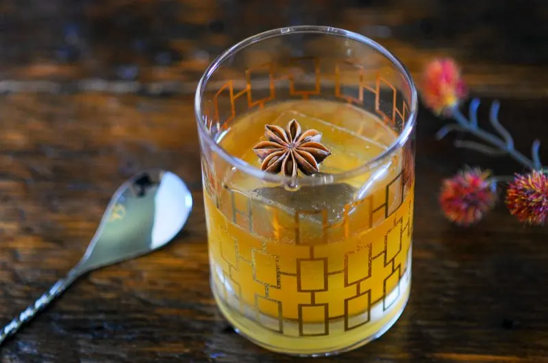Brown butter bourbon cocktail in glass with star anise on ice