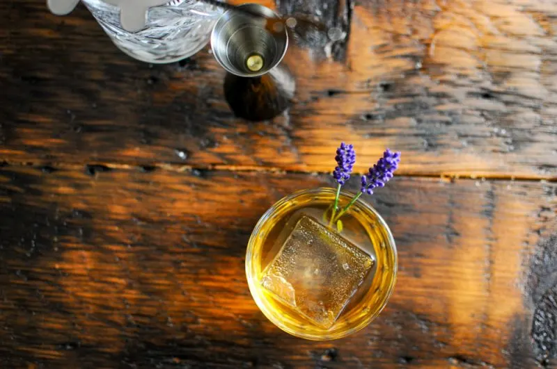 Top shot of whiskey cocktail, clear ice and lavender sprigs
