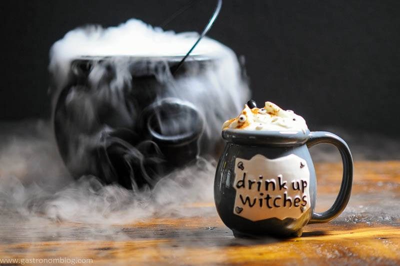 Gray cauldron with cocktail, topped with whipped cream and eye candies for Halloween