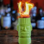 Green Tiki mug with zombie cocktail and flames