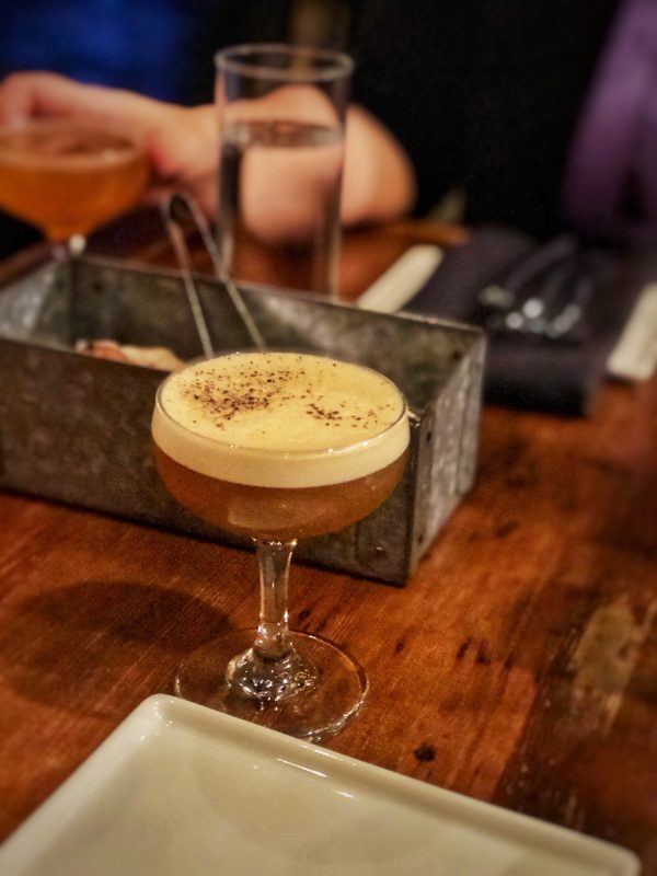 Cocktail at Brazen Open Kitchen, topped with egg foam. Metal bread basket in background