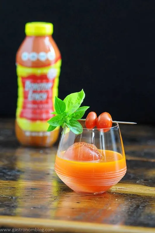 Orange cocktail in glass with tomatoes and basil, Dorothy Lynch bottle in background