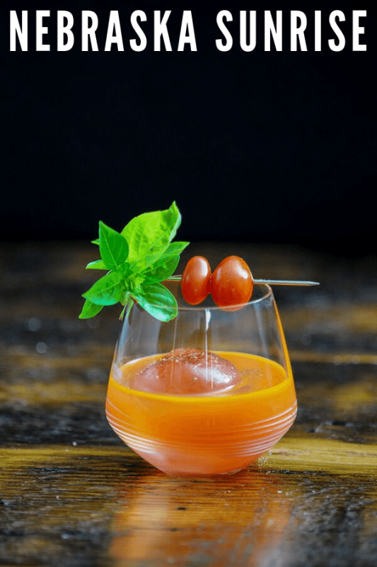 Orange cocktail in glass with basil and tomatoes