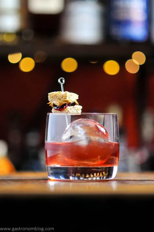 Peanut Butter and Jelly Cocktail in rocks glass, tiny PB & J sandwich garnish