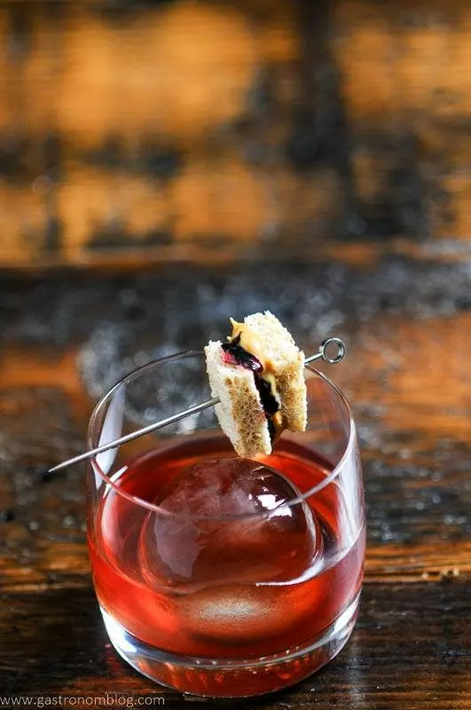 Pink cocktail in rocks glass, sandwich garnish