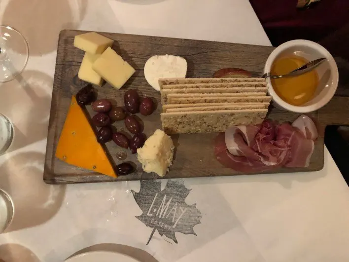 Cheese Tray at L May Eatery, olives, cheese, meat and crackers with honey in white ramekin