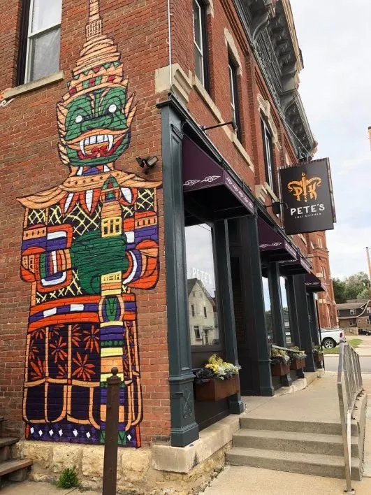 Pete's Thai Restuarant in a brick building, statue painting on side of building