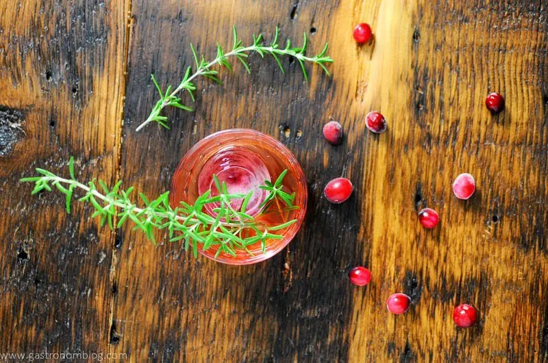 Top shot of red cocktail with cranberries and rosemary
