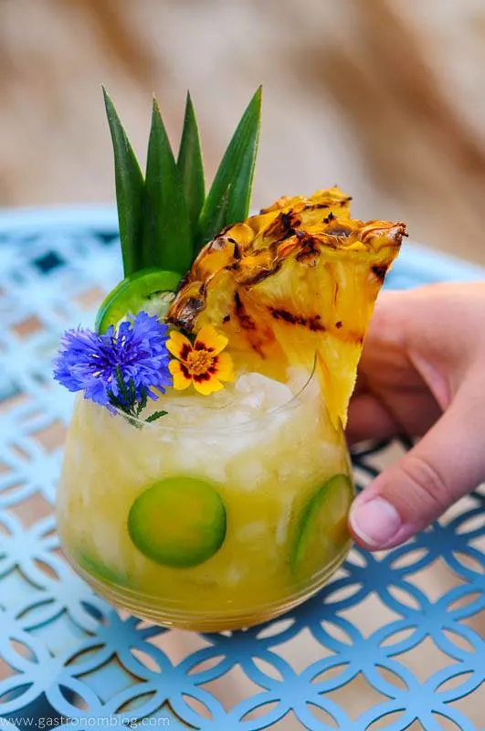Yellow cocktail with pineapple slice and flowers