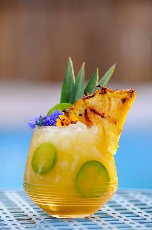 Yellow cocktail with pineapple and edible flowers