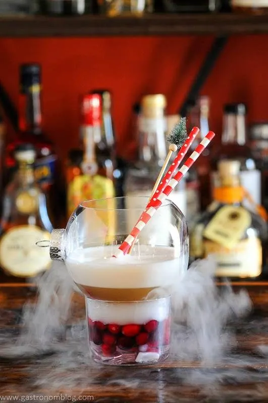 Cocktail in ornament for Christmas with dry ice, red and white straws