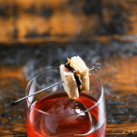 Pink cocktail in rocks glass with tiny pb&j sandwich
