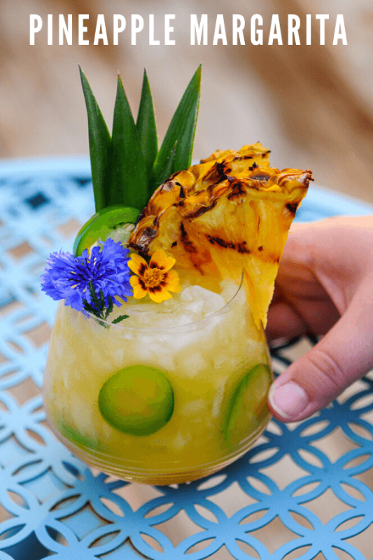 Yellow cocktail in glass with edible flowers