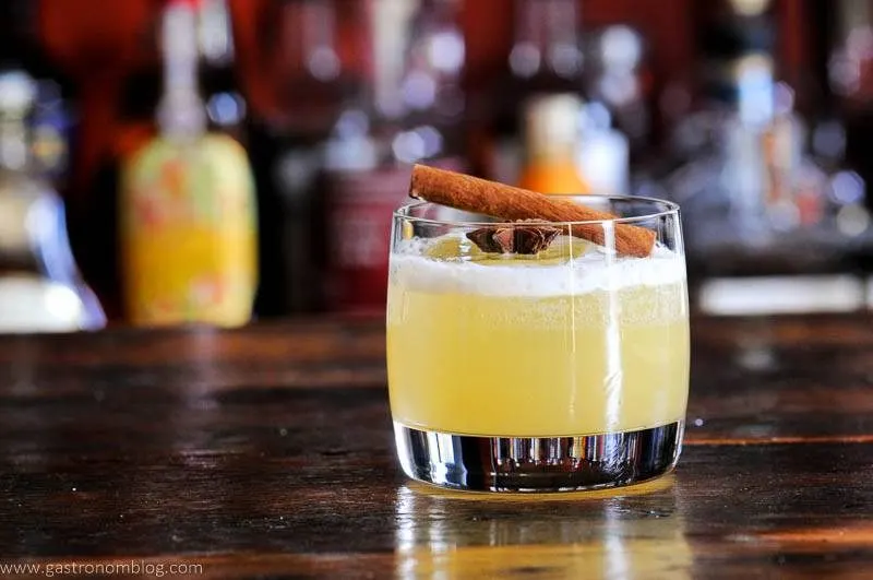 yellow Spiced Gin Punch in rocks glass with spices on top, cinnamon stick and star anise