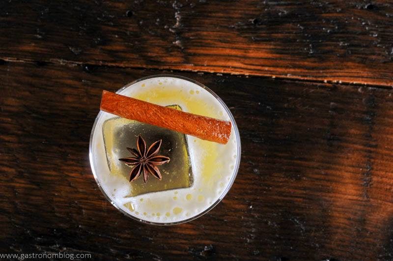 Top shot of cocktail with cinnamon stick and star anise on top of ice cube