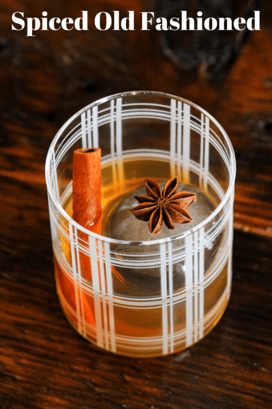 brown Whiskey cocktail in striped glass, cinnamon stick and star anise