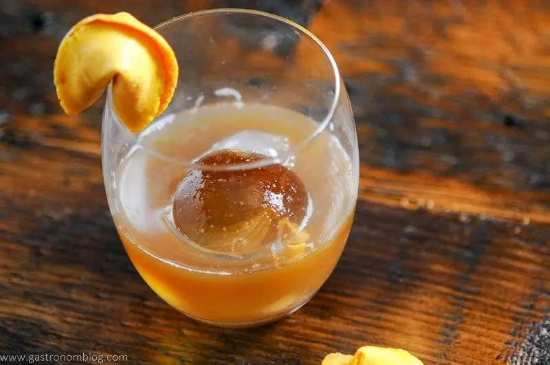 Tan cocktail with clear ice, fortune cookie