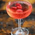 Pink cocktail in coupe with raspberries
