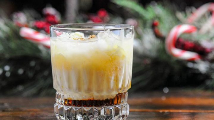 Cocktail in rocks glass, creamy layer on top, brown layer on bottom. evergreen and candy canes in background
