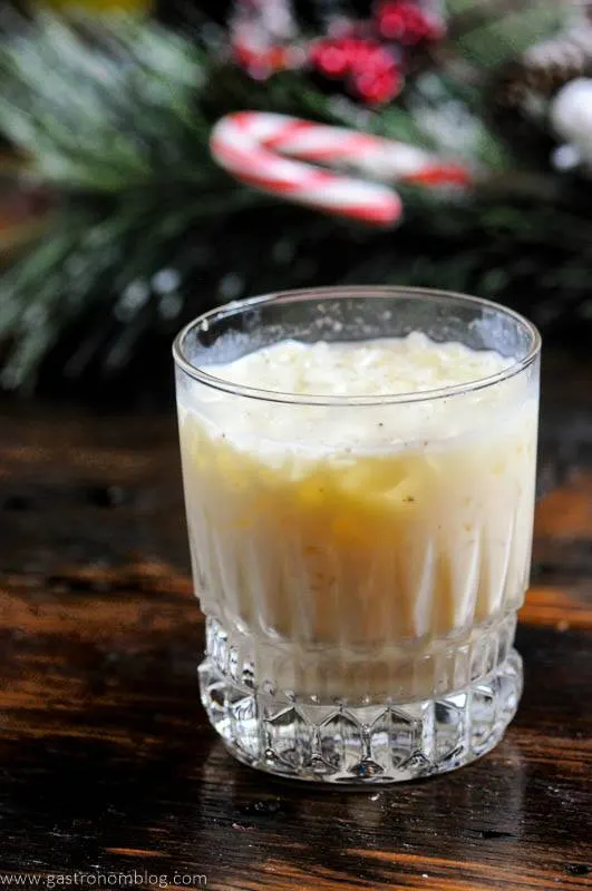 White cocktail on wood board, evergreen behind